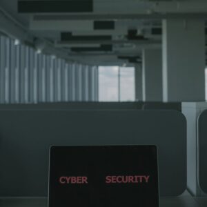 Laptop displaying 'Cyber Security' in a modern office setting, emphasizing tech and cybersecurity themes.